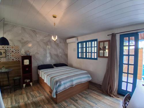 a bedroom with a bed and a table and a window at Santa Monica Beach Tiny House in Guarapari
