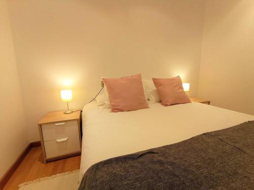 a bedroom with a bed with two lamps on it at Apartamento Playa Foz in Foz