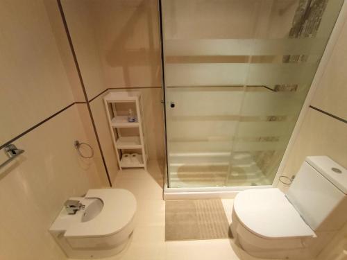 a small bathroom with a toilet and a shower at Apartamento Playa Foz in Foz
