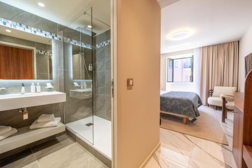 a bathroom with a shower and a bed in a room at Hotel Beau Rivage in Nice
