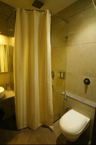 a bathroom with a shower curtain and a toilet at hotel manjushree in Pachmarhī