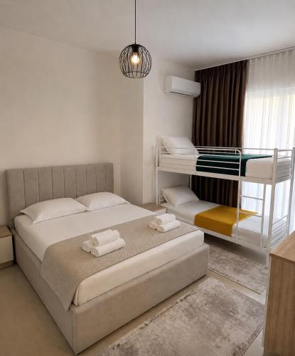 a white bedroom with a bed and a desk at Ayzal Apartment in Shëngjin