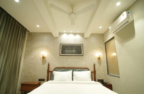 a bedroom with a bed with white sheets at hotel manjushree in Pachmarhī