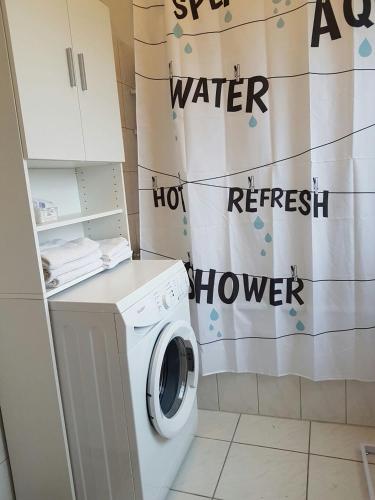 a washing machine in a bathroom with a shower curtain at City Apartment in Düren - Eifel