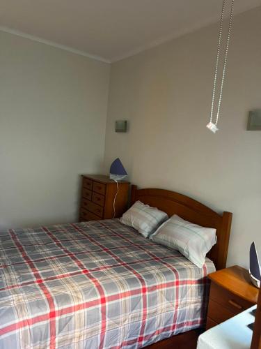 a small bedroom with a bed with a plaid blanket at Sol e Praia in Figueira da Foz