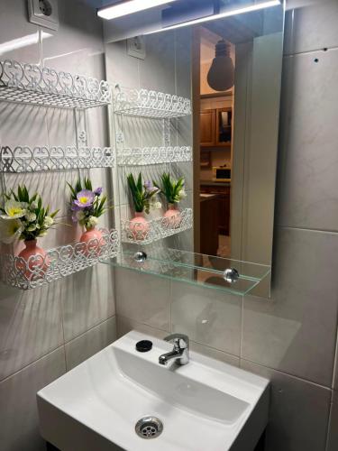a bathroom with a sink and a mirror and flowers at Sol e Praia in Figueira da Foz