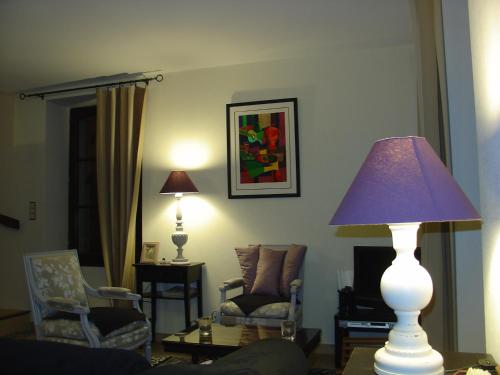 a living room with a table with a lamp and chairs at La Sabotiere in Plumeliau Bieuzy