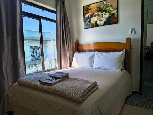 a bedroom with a bed with a window and towels on it at Loft Carminatti in Cacoal