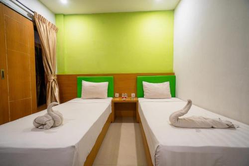 two beds in a room with two swans on them at Melati Hotel central kuta mandalika in Kuta Lombok