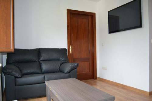 Albergue Belén في Belén: غرفة معيشة مع أريكة جلدية سوداء وتلفزيون بشاشة مسطحة