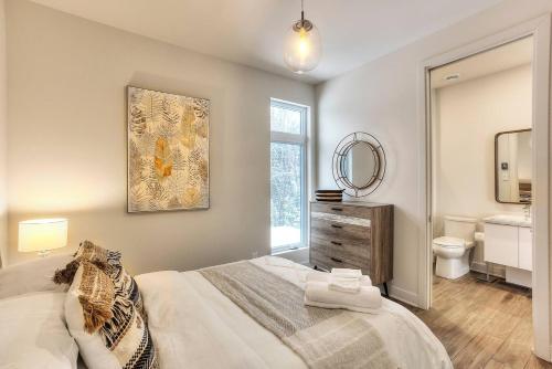 a bedroom with a bed and a bathroom with a mirror at Tremblant Summit: Travel Experience Beyond Compare in La Conception