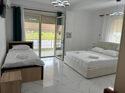 two beds sitting in a room with a window at Radhima Sun Studio in Vlorë