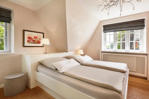 a bedroom with a bed and two windows at Reethus Nordstil in Borgsum