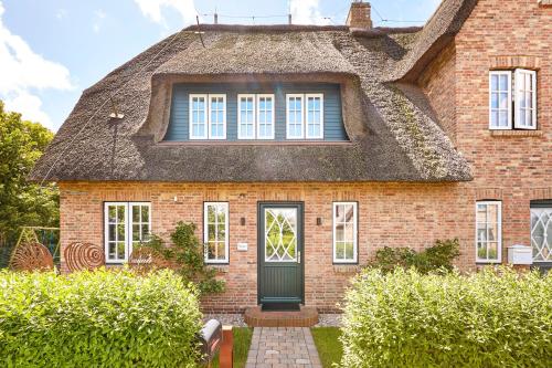 an old brick house with a thatched roof at Reethus Nordstil in Borgsum