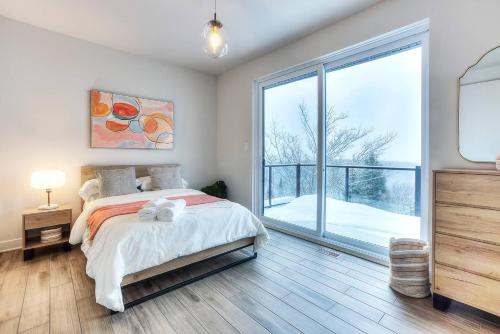a bedroom with a bed and a large window at Tremblant Summit: Travel Experience Beyond Compare in La Conception