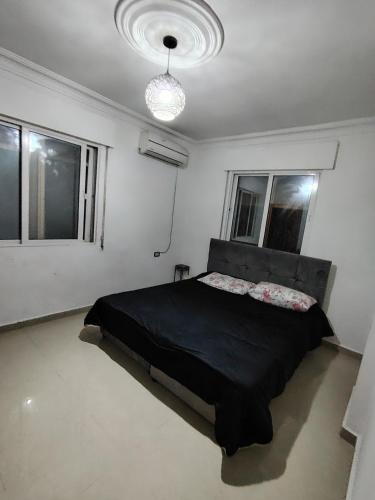 ein Schlafzimmer mit einem schwarzen Bett in einem Zimmer mit Fenstern in der Unterkunft شقة ريماس in Irbid
