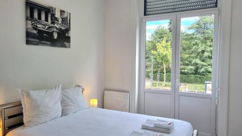a white bedroom with a bed and a window at AGENCE MOMENT'APART Legend in Mouvaux