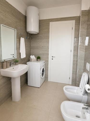 a bathroom with a sink and a washing machine at Ayzal Apartment in Shëngjin