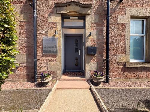 a brick building with a blue door and two plants at Winmar Guesthouse in Inverness