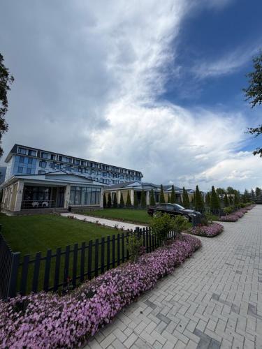 a building with a fence and flowers in front of it at Novel Hotel&Apartaments in Korumdy