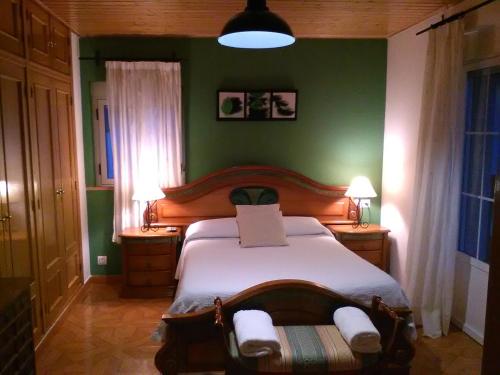 1 dormitorio con cama y pared verde en Casa Rural La Esmeralda, en Navarredonda de Gredos