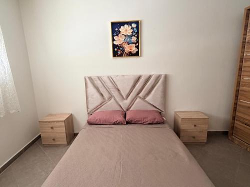 a bedroom with a bed with a headboard and two night stands at Location meublée Martil in Martil