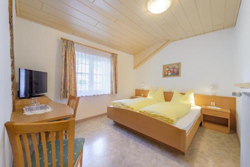 a bedroom with a bed and a desk and a television at Micheli Hermann Obst- und Weinbauernhof mit "Südtirol Alto Adige Guest Pass - Mobilcard" in Caldaro