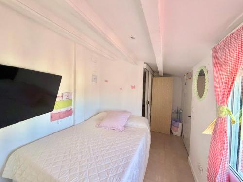 a small bedroom with a bed and a flat screen tv at Habitación con baño y cocina in Caudiel