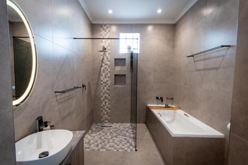 a bathroom with a shower and a tub and a sink at Meerkat Manor Self-Catering & Accommodation Windhoek in Windhoek