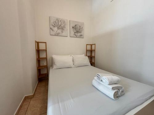 a bedroom with a white bed with towels on it at Sisifou Apartment in Korinthos
