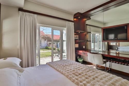 a bedroom with a bed and a desk and a television at Homestead Villas in Bellville