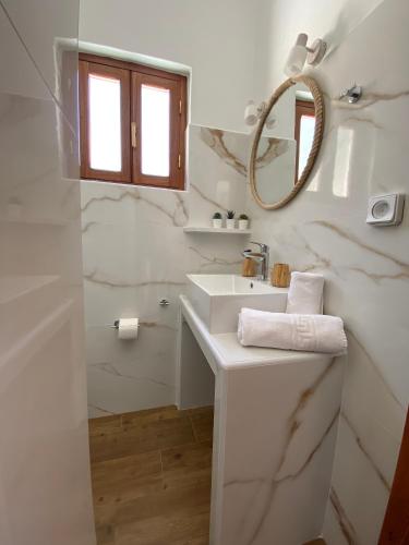 a white bathroom with a sink and a mirror at Apolafsis Studios in Patmos