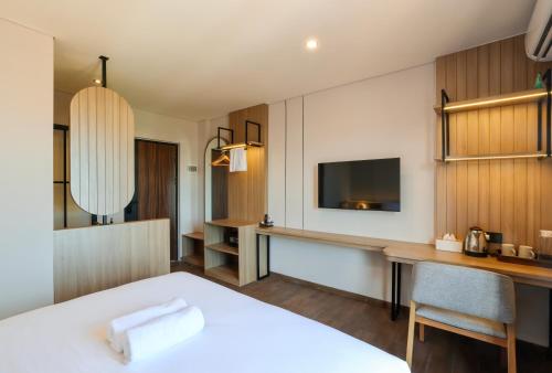 a hotel room with a bed and a desk and a television at The Dyastana Umalas in Kerobokan