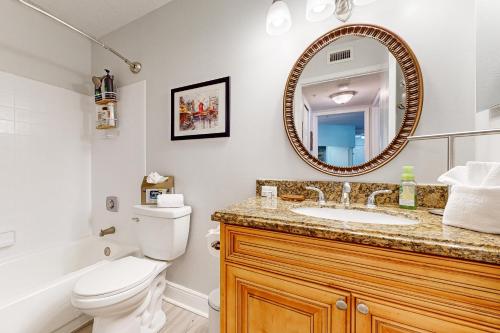 a bathroom with a toilet and a sink and a mirror at Cypress Cove 111 in Melbourne