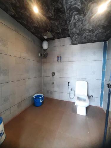 a bathroom with a toilet and a blue bucket at CP Villa Resort in Bhāweghar