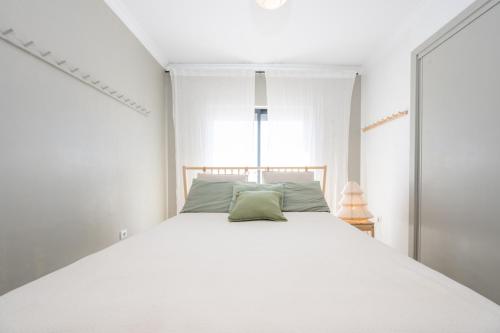 a bedroom with a white bed with a green pillow at Rivara Rooftop By ALGARTUR in Cabanas de Tavira