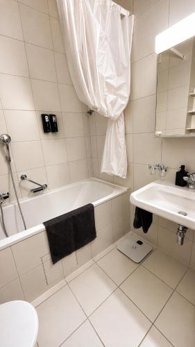 a white bathroom with a tub and a sink at Petit Canada - Studio à louer in Champex