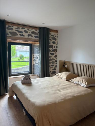 a large bed in a bedroom with a window at Maison en Auvergne - Chez Julien et Stephy in Celles