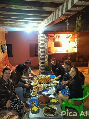 a group of people sitting around a table eating food at Gite Oussalem timichi in Timichchi