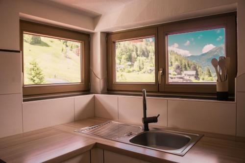 a kitchen with a sink and two windows in it at Landhaus am Hügel in Bad Gastein