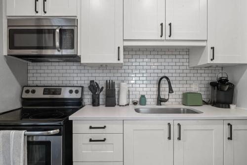 a kitchen with white cabinets and a stainless steel sink at The Cedar Loft B - Team Joseph Ellen in St. Augustine