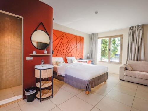 a bedroom with a bed and a mirror and a chair at Ibis Styles Mayotte Aéroport in Pamandzi