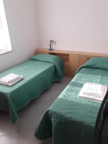 two beds in a room with green sheets at Doroteafarm, dove saltiamo sull'amore e i sogni in Scalea