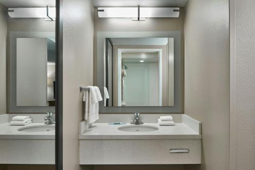 a bathroom with two sinks and two mirrors at SpringHill Suites by Marriott Atlanta Alpharetta in Alpharetta