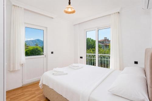 a white bedroom with a bed and a large window at Daisy Villa in Dalyan