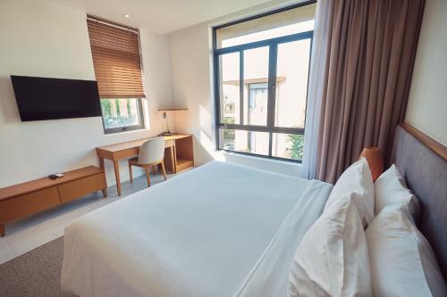 a hotel room with a bed and a desk and window at Sunrise Pool Villa Cam Ranh in Cam Ranh