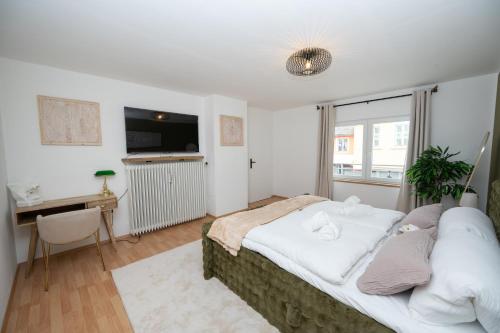 a bedroom with a bed and a desk and a window at Green Mango - City Apartment mit Balkon in Mürzzuschlag