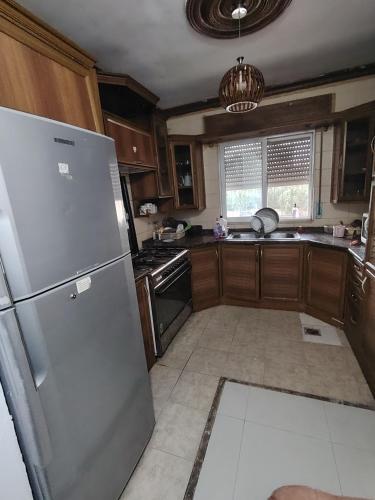 a kitchen with a stainless steel refrigerator and wooden cabinets at شقة سرايا in Irbid