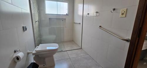 a white bathroom with a toilet and a shower at Apartamento da Dani in Guaratinguetá