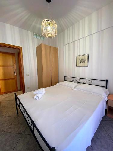 a bedroom with a large white bed with a chandelier at Bentu e Soli Home Holiday in Villasimius